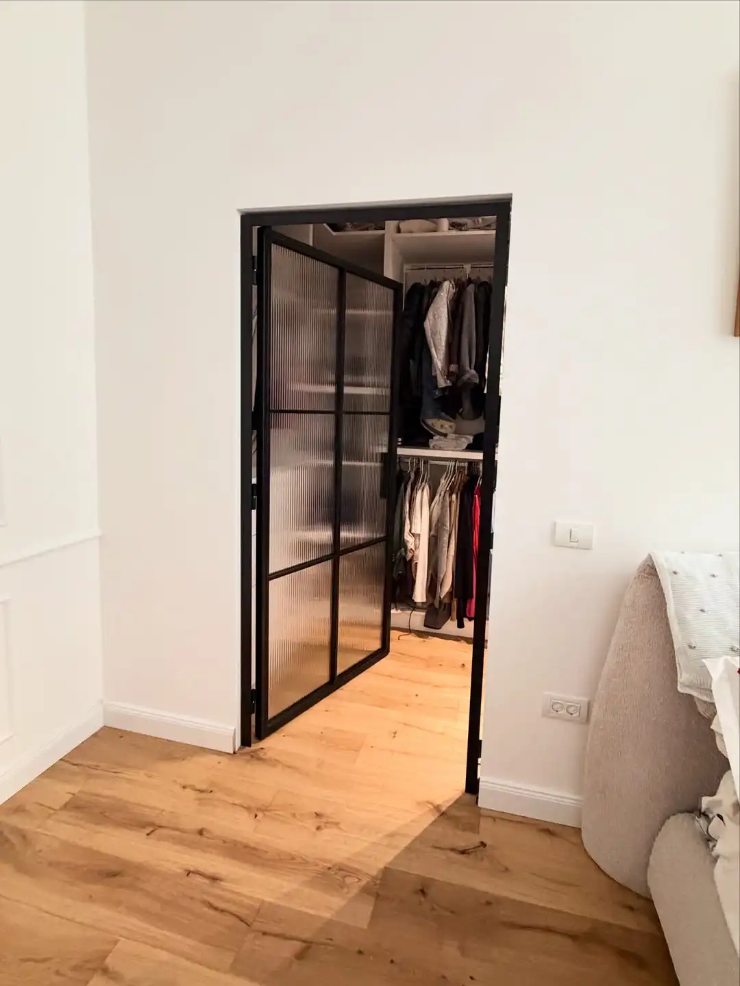 Ușă de dressing din metal și sticlă riflată, deschisă spre garderobă